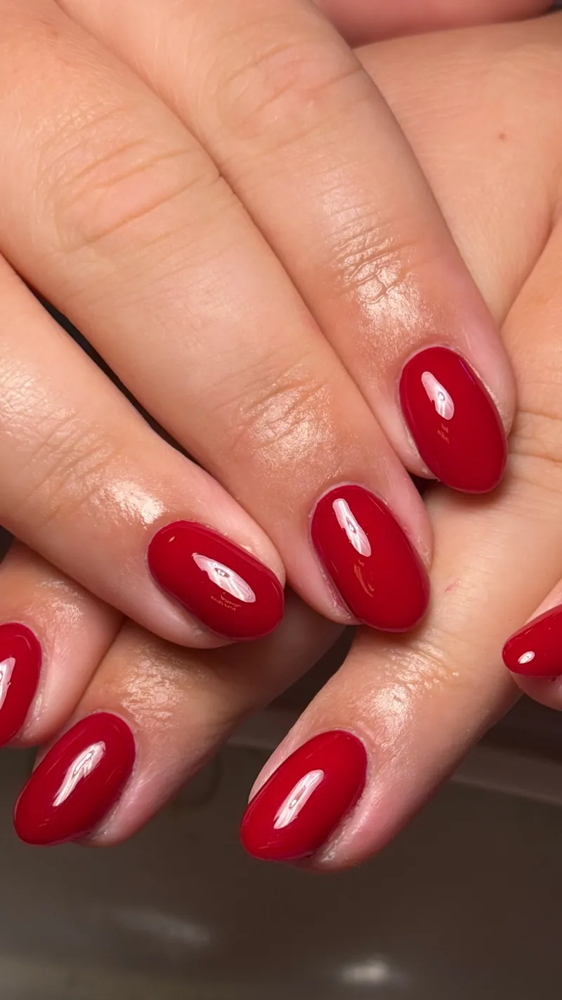 Glossy red oval nails seen close up, by Rosie Mae Beauty